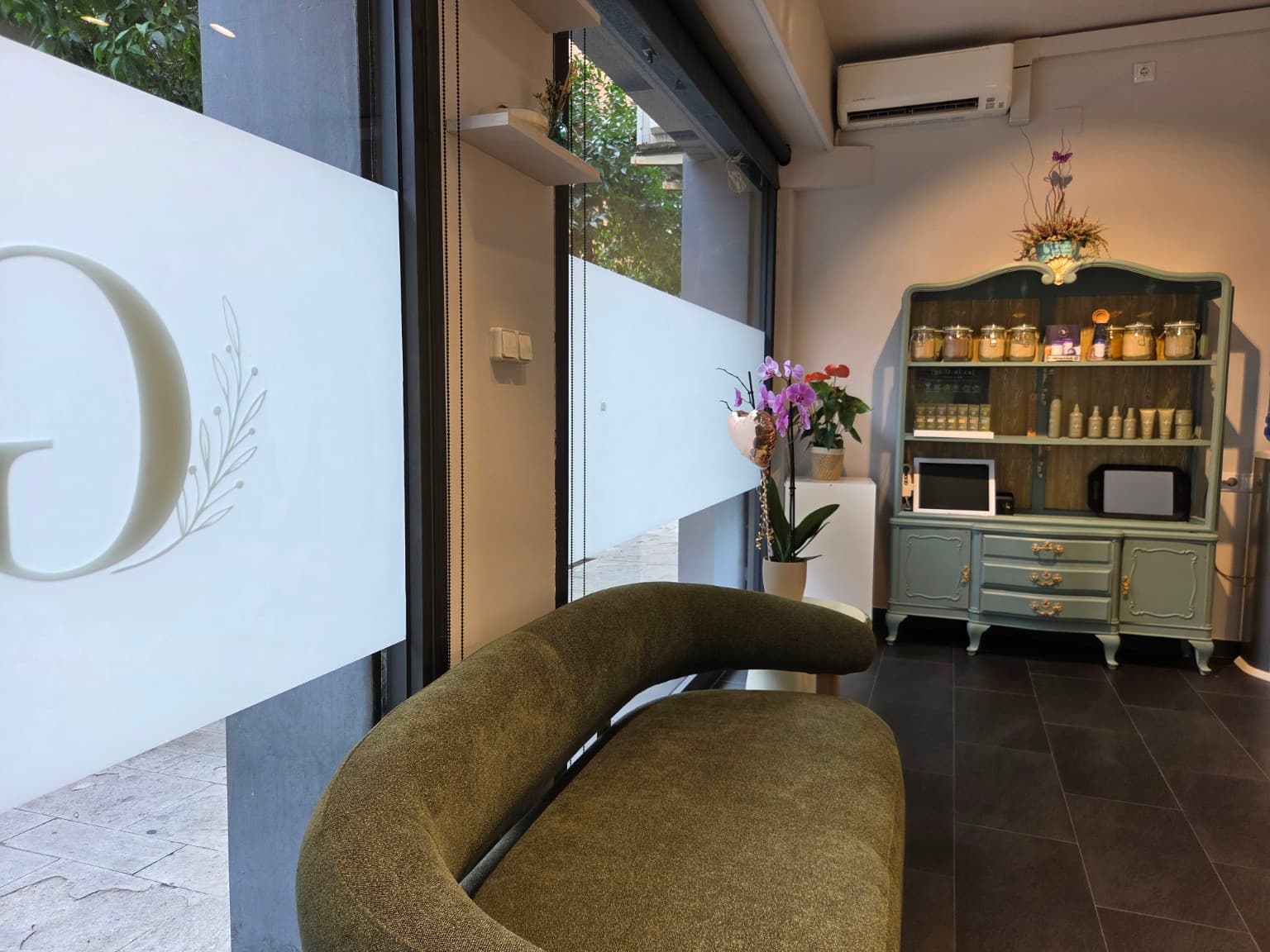 Zona d'espera de Gio Studio amb sofà verd, orquídia i aparador